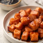 Close-up of air fryer salmon bites glazed with soy sauce on a white plate