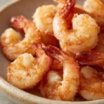 Close-up of crispy air fryer shrimp with cornstarch on a white plate.