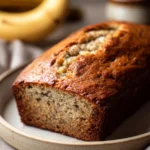Close-up of a moist banana bread slice with a golden crust and soft interior.