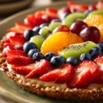 Close-up of an oatmeal cookie fruit pizza topped with fresh fruits on a clean background