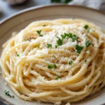 Close-up of creamy parmesan pasta in a white bowl with a sprinkle of herbs