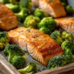 Salmon and Broccoli Sheet Pan Dinner for a Cozy Night In 3 Close-up of a salmon and broccoli sheet pan dinner with bright, warm lighting.