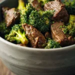 Close-up of slow cooker beef and broccoli with bright lighting and minimal background.