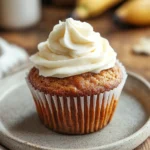 Close-up of banana muffins with icing on a clean background, highlighting texture and detail.