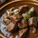 Close-up of beef tips and gravy in a rich sauce with a clean background.
