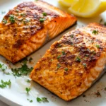 Close-up of frozen salmon cooked in an air fryer with a golden crust and garnished with herbs.