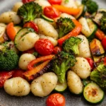 Close-up of a vibrant gnocchi sheet pan dinner with vegetables and herbs, showcasing a vegan meal.