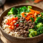 Close-up of a high protein beef and rice bowl with vibrant vegetables and a clean background.