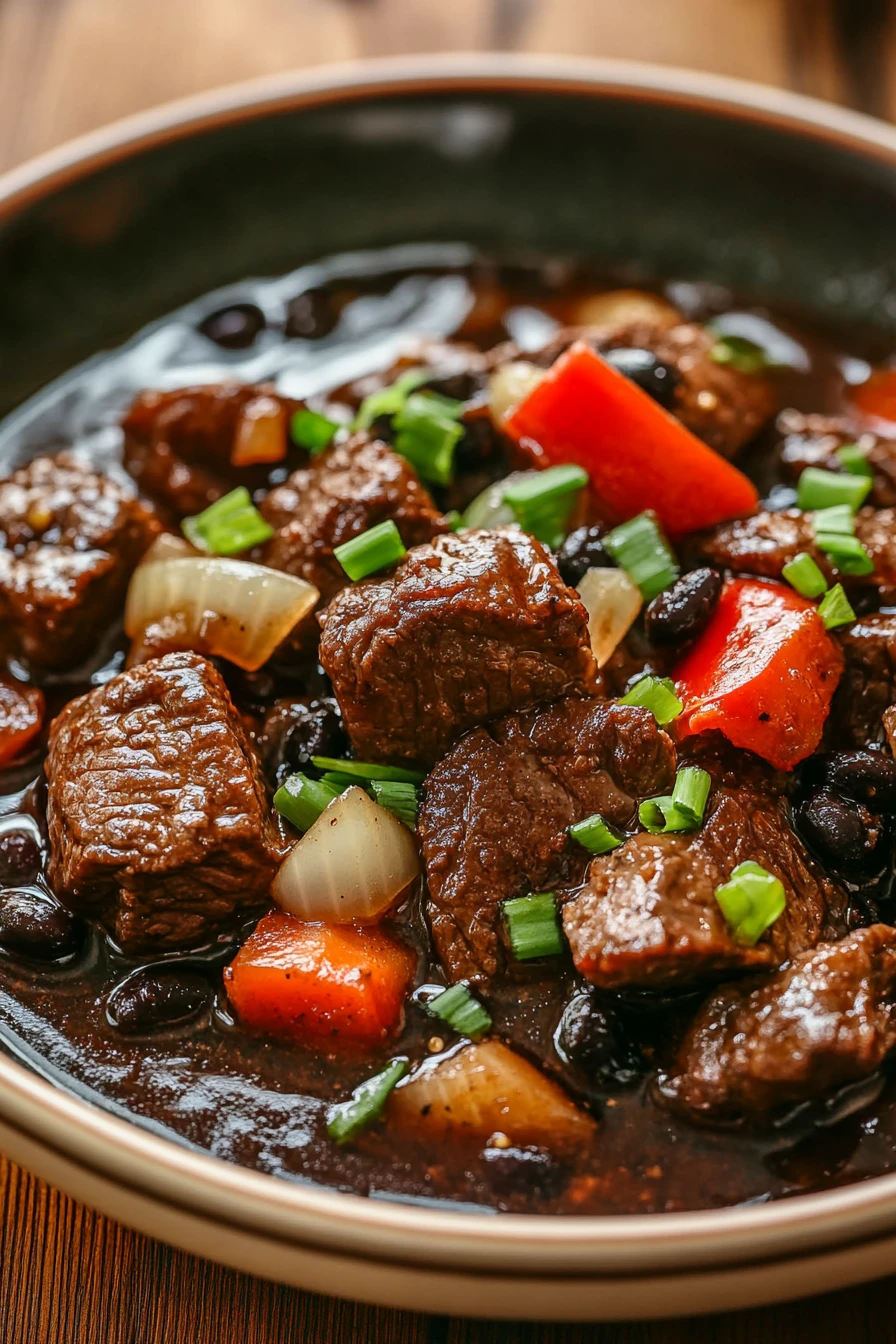 Close-up of slow cooker beef in black bean sauce with vibrant colors and textures