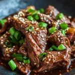 Close-up of slow cooker Korean beef with a rich, savory sauce and garnished with green onions.