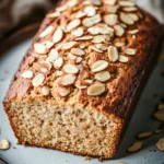 Close-up of zucchini almond bread with a golden crust and almond slices on top